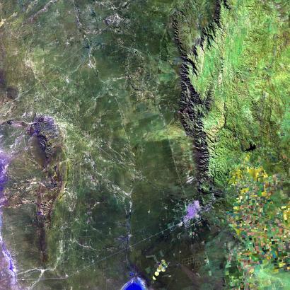 aerial satellite image of town, cropland, and mountains