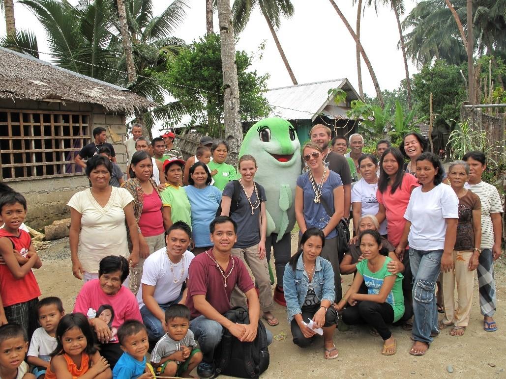 emLab researches and partners from Rare and EDF posing alongside villagers with "Robata the Rabbitfish," the mascot for the local Pride campaign