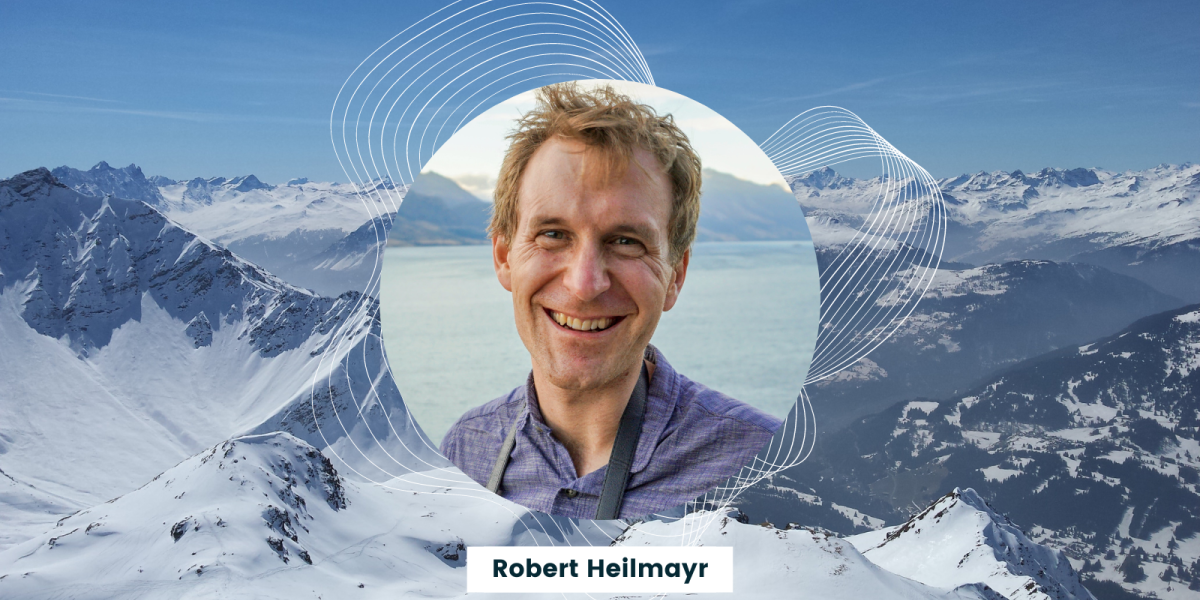 robert heilmayr headshot with snowy mountains in the background