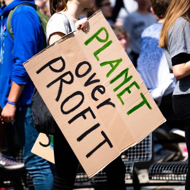 protest with a sign that says planet over profit