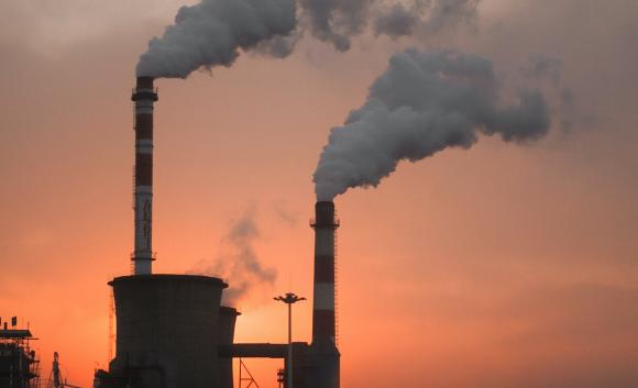 factory smokestacks emitting smoke at sunset